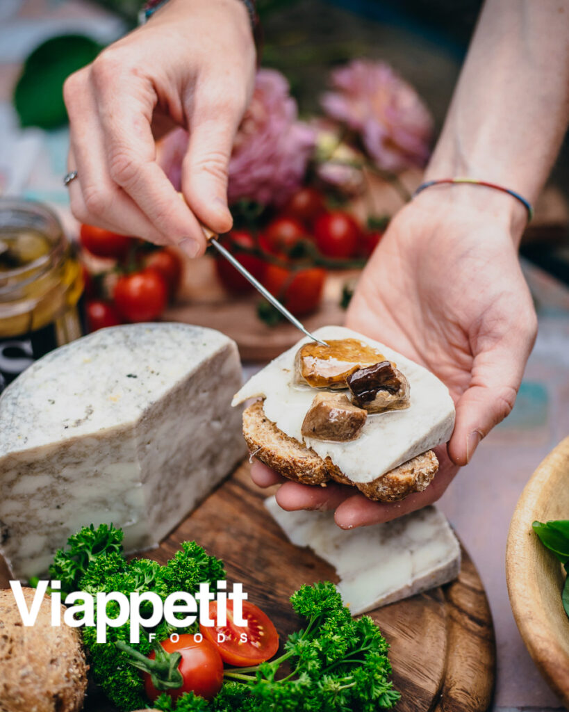 Tabla de quesos. Aparecen las manos de una persona sosteniendo un plato con varios quesos
