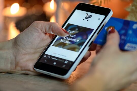 imagen de portada del artículo sobre ciberdelincuencia en el comercio electrónico en la que aparece una mano sosteniendo un smartphone con el que interactua
