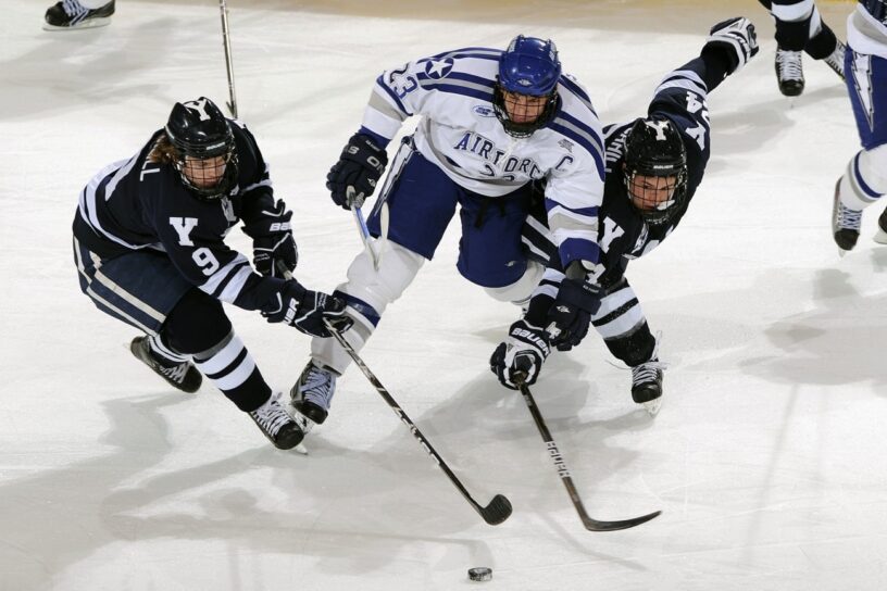 imagen en la que aparecen tres jugadores de hockey sobre hielo disputando por el disco