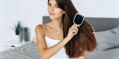 Imagen de portada del artículo sobre cómo mantener un cabello sano en la que aparece una mujer cepillando su cabello moreno, laceo y largo